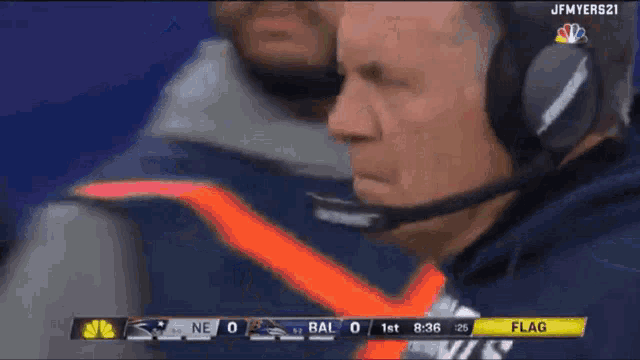 a man wearing headphones and a microphone watches a football game between bal and ne