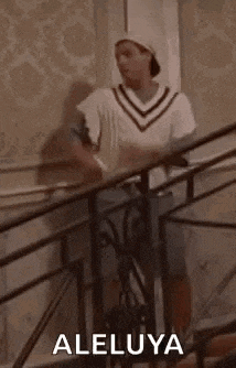 a man is standing on a set of stairs wearing a hat and a sweater .