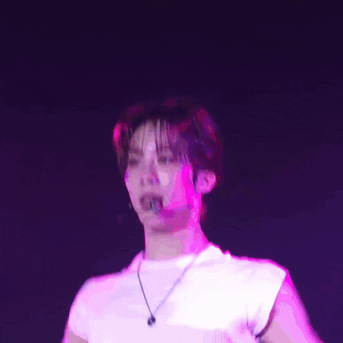 a blurry picture of a man in a white shirt with a purple light behind him .
