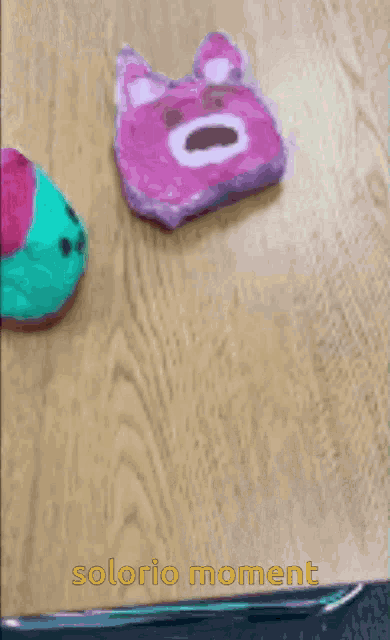 a drawing of a pink teddy bear on a wooden table with the words solorio moment above it