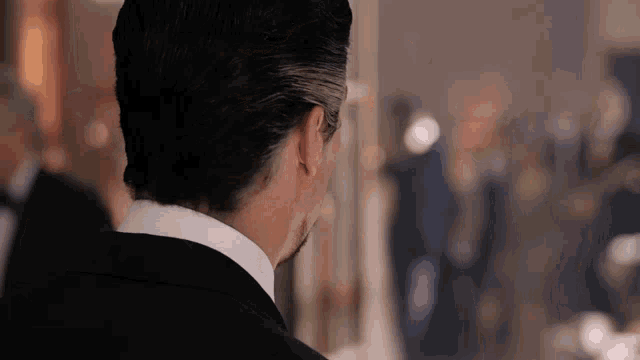 a man in a tuxedo looks at a painting