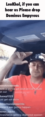 a man in a red shirt is sitting in the driver 's seat of a car and making a funny face