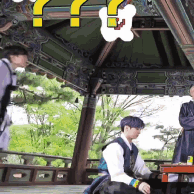 a man with purple hair is sitting at a table under a gazebo
