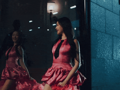 a woman in a red dress stands in front of a window