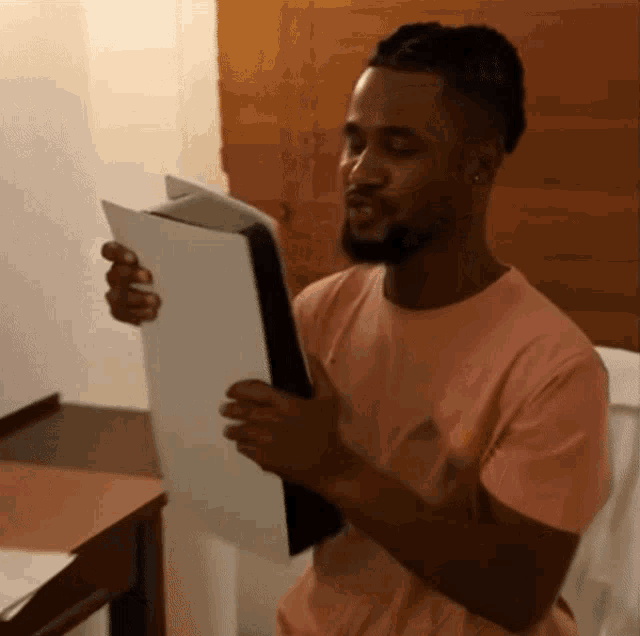 a man in a pink shirt is holding a piece of paper in his hands