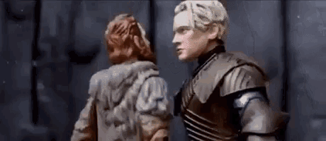 a man and a woman in armor are standing next to each other in a dark room .