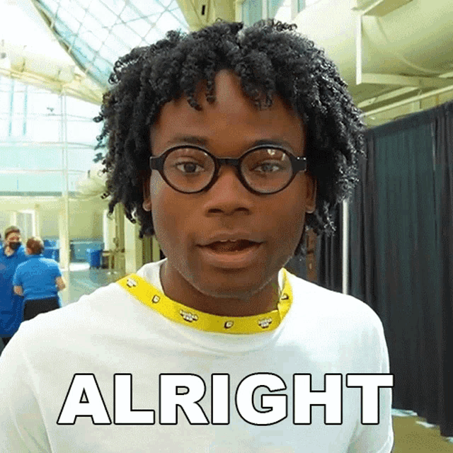 a man wearing glasses and a white shirt with the word alright written on it