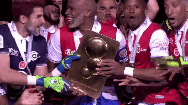 a group of soccer players are holding a trophy that says grand reims