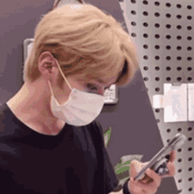 a man wearing a mask is looking at his cell phone .