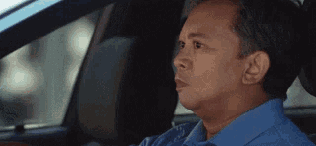 a man is sitting in the driver 's seat of a car and making a funny face .
