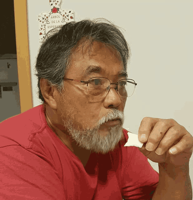 a man with glasses and a beard is eating a piece of food
