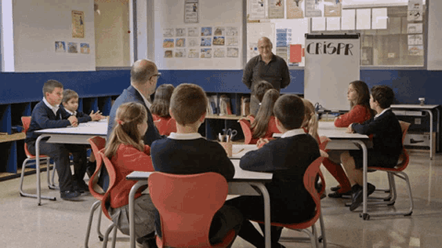 a group of children sit at their desks in front of a whiteboard that says crispr