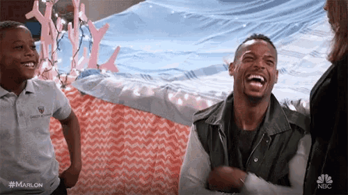 a man is laughing while standing next to a boy and a woman