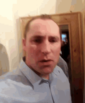 a man in a light blue shirt is taking a selfie