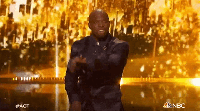 a man in a suit is dancing on a stage with the nbc logo in the corner