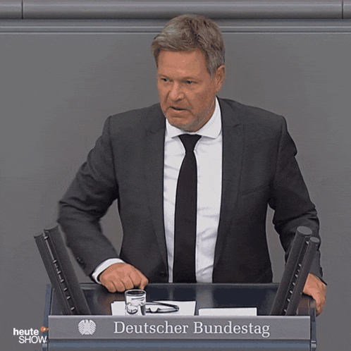 a man stands at a podium that says deutscher bundestag on it