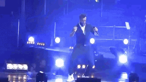 a man is standing on a stage holding a microphone and dancing .