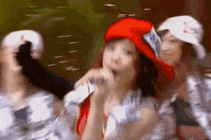 a woman wearing a red hat is singing into a microphone while dancing .