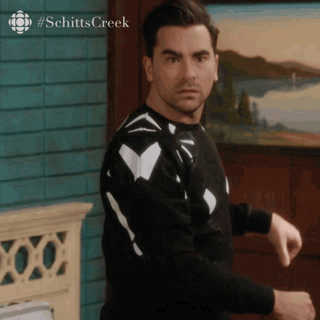 a man wearing a black and white sweater with the word schitts creek on the bottom