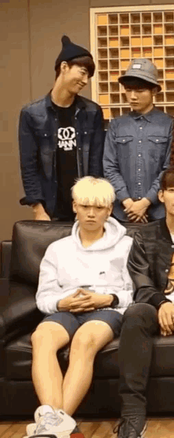a group of young men are sitting on a couch with one wearing a shirt that says ' snn '
