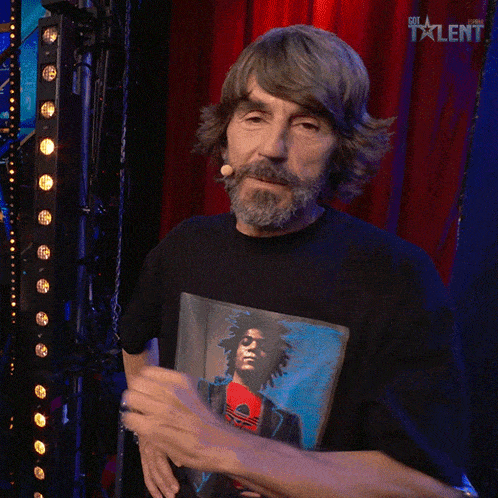 a man with a beard is wearing a black shirt with a picture of jimi hendrix on it and says claro que si