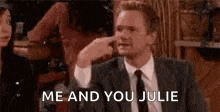 a man in a suit and tie is sticking his finger in his nose and saying `` me and you julie '' .