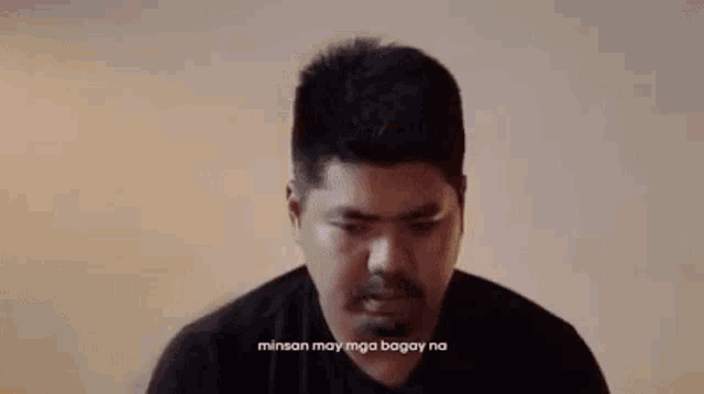 a man in a black shirt is sitting in front of a wall with the words hindi ko naiintindihan ko naman .
