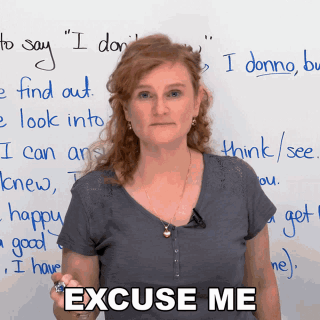 a woman stands in front of a white board with the words " excuse me " written on it