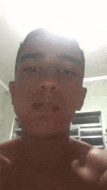 a young man without a shirt looks at the camera