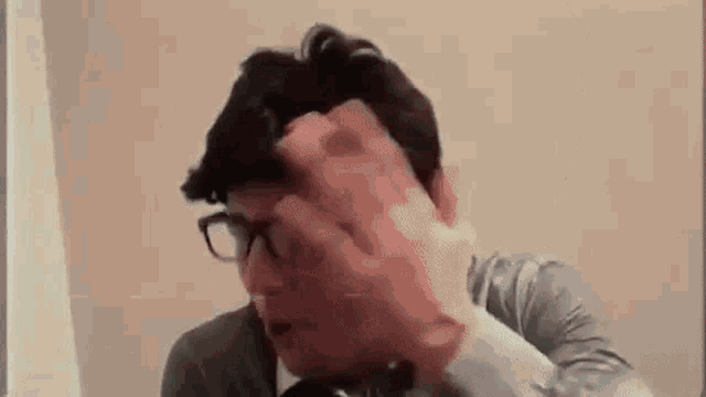 a man with glasses is making a funny face with his hands .
