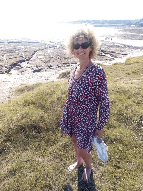 a woman in a floral dress is standing in a field