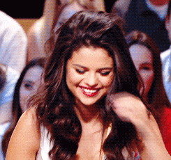 a woman with long brown hair is smiling in a crowd