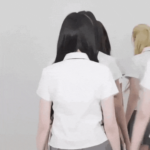 a group of girls in school uniforms are standing next to each other holding hands .