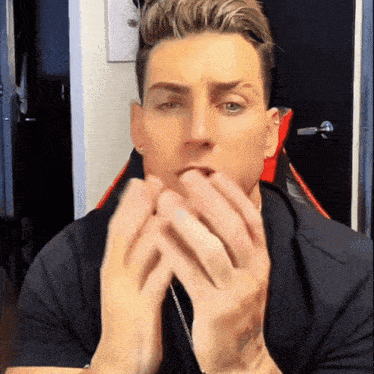 a man covering his mouth with his hands while looking at the camera