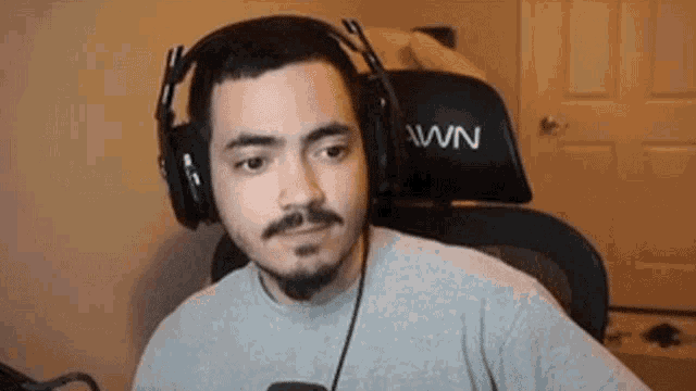 a man with a beard is wearing headphones and sitting in a gaming chair .