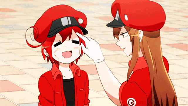 a girl in a red uniform is touching another girl 's hat