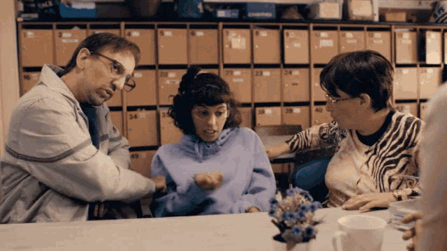 a woman wearing a zebra print shirt sits at a table with a man and a girl
