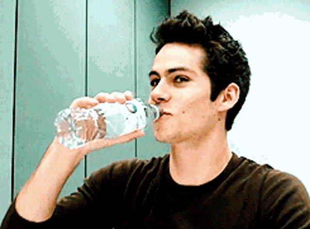 a young man is drinking water from a bottle that says aquafina