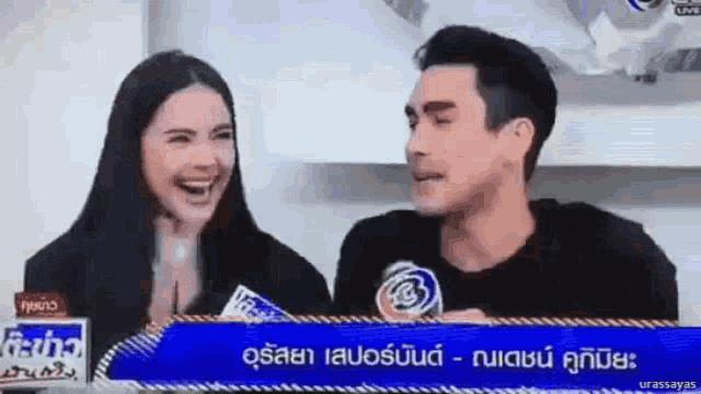 a man and a woman are sitting next to each other laughing .