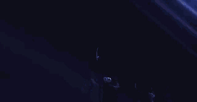a group of people are standing in the dark with a blue light coming from the ceiling .