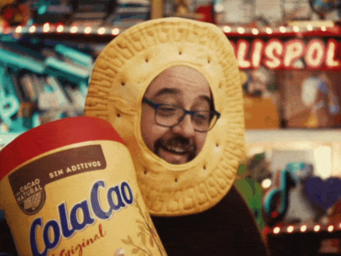 a man is wearing a cookie costume and holding a cola cao