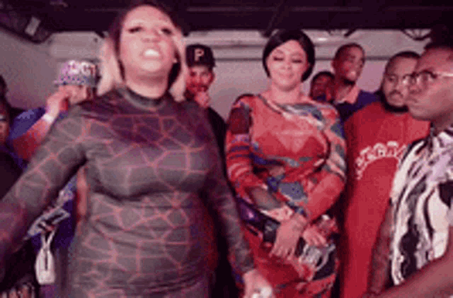 a group of people standing in a room with a woman in a red dress
