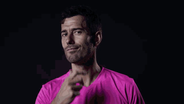 a man in a pink shirt is pointing at something