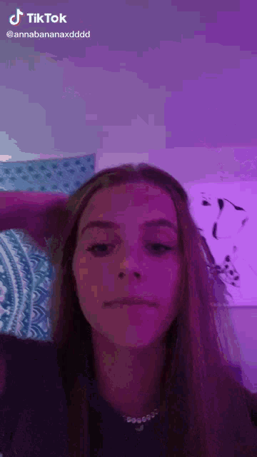 a girl with long hair is making a funny face in front of a purple background .