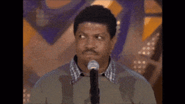 a man is standing in front of a microphone and looking at the camera