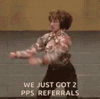 a woman is dancing in front of a brick wall with the words `` we just got 2 pps referrals '' .