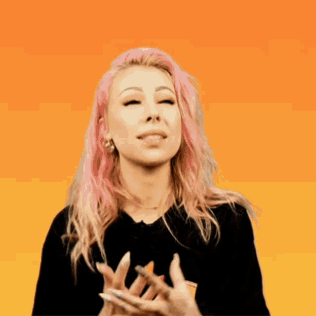 a woman with pink hair is making a face with her hands