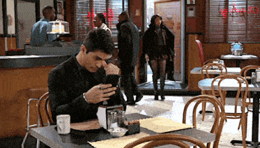 a man sits at a table in a diner looking at his cell phone