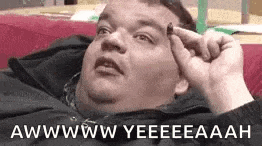 a fat man is laying on a couch with his hand on his head .
