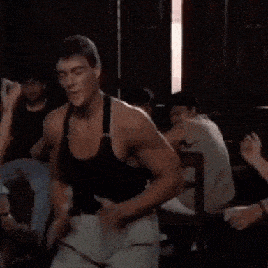a man is dancing in a room with people sitting at tables and chairs .